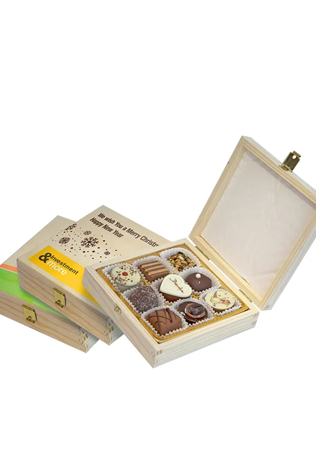 Offene Schachtel mit verschiedenen Pralinen, umgeben von zwei geschlossenen Schachteln.
